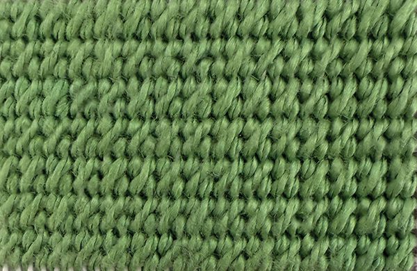 Mosaic stitch worked in green thread, a small dense block stitch that fills a needlepoint background quietly.