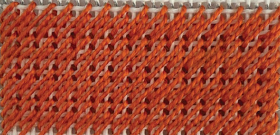Nobuko stitch worked in orange thread on white needlepoint canvas, showing the soft diagonal ripple it creates across a background.