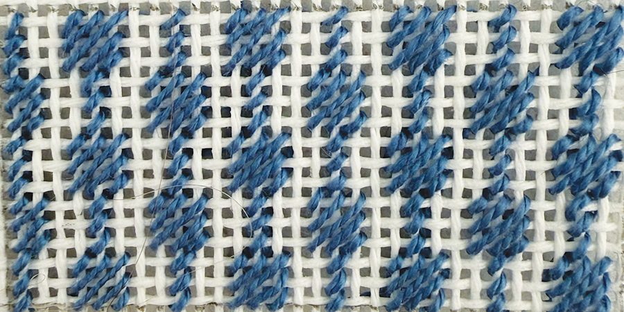 Scotch stitch, tent variation, worked in blue thread on white needlepoint canvas — a large block framed with tent stitch.